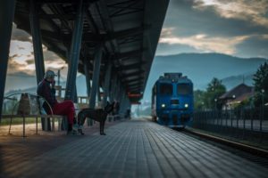 Ein Mann sitzt mit seinem Hund an einem Bahnsteig